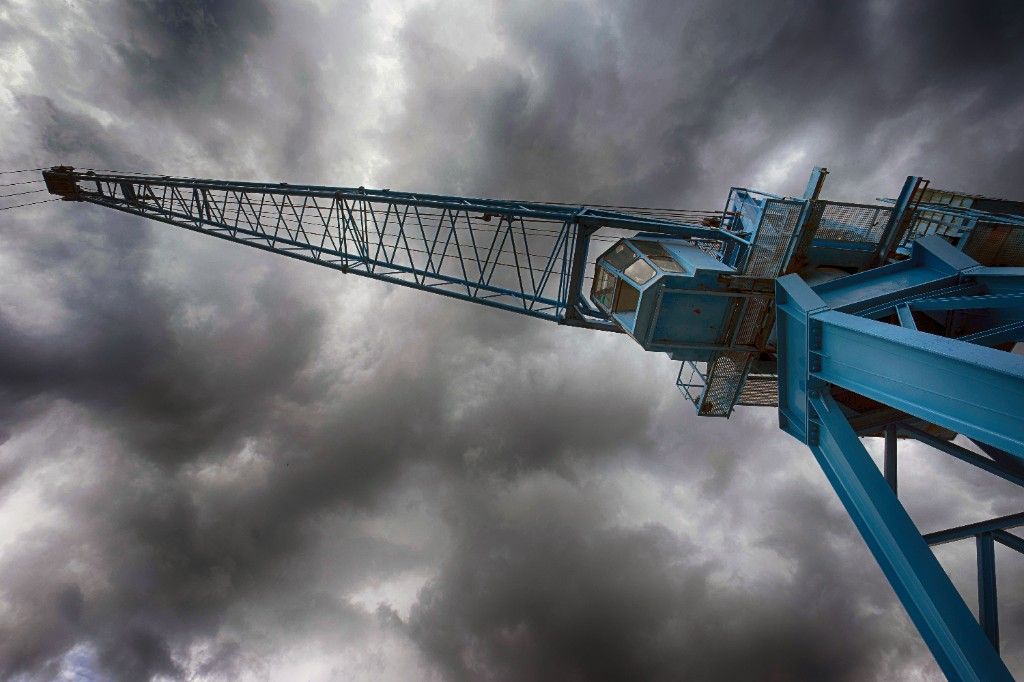 Blue harbour crane seen from below against dark clouds