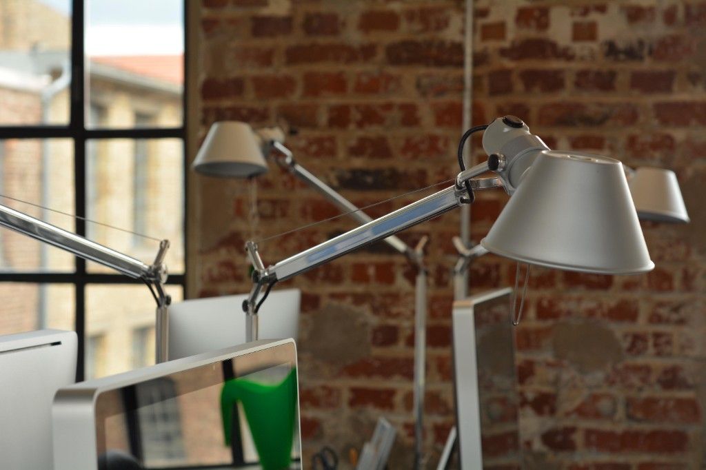 Desk lamps and monitors in front of a brick wall