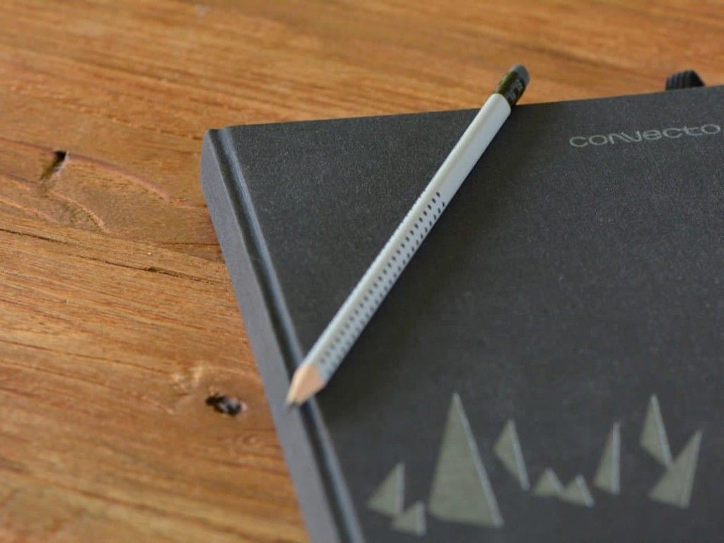Notebook with the Convecto logo and a pencil on a wooden table
