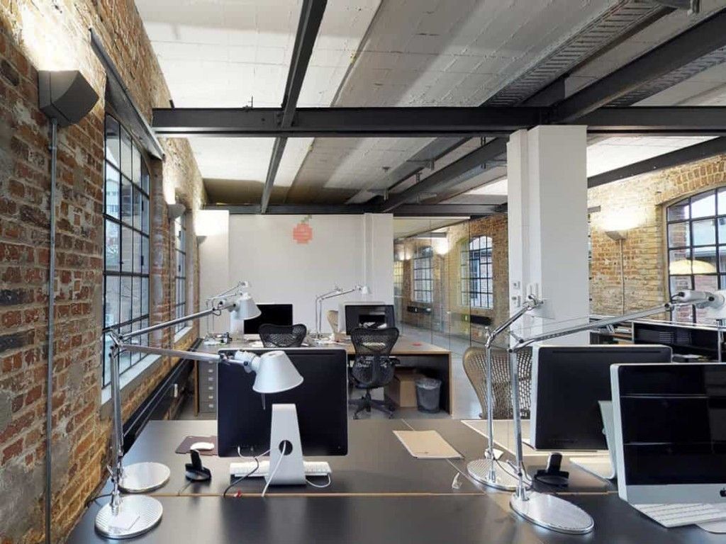Desks in the office with brick walls, steel beams and factory windows
