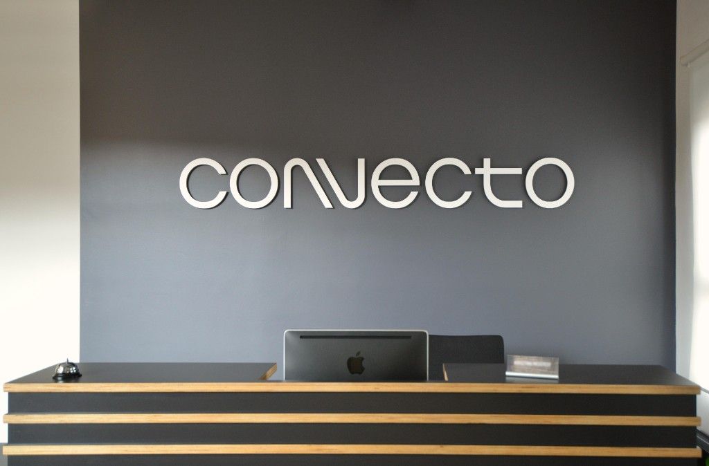 Reception desk below the Convecto lettering on a dark grey wall
