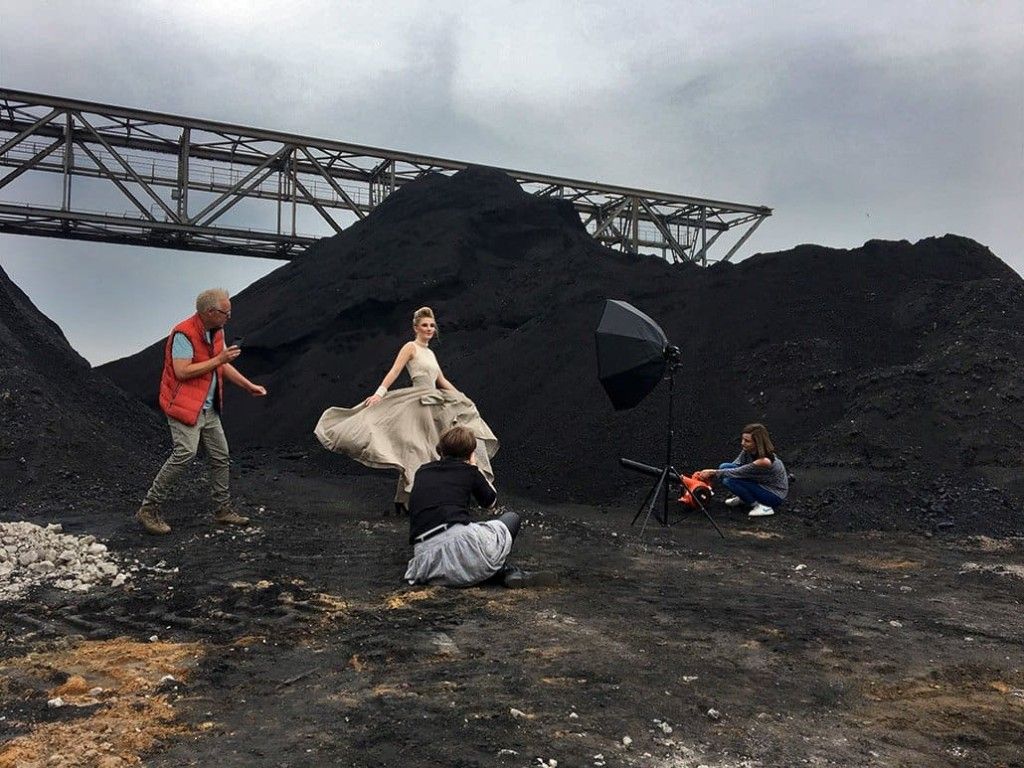 Photo shoot in front of a black heap: a model in an evening gown, the photographer and the crew