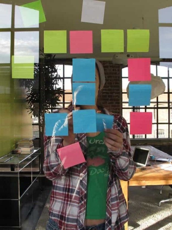 A colleague arranging coloured sticky notes on a glass wall