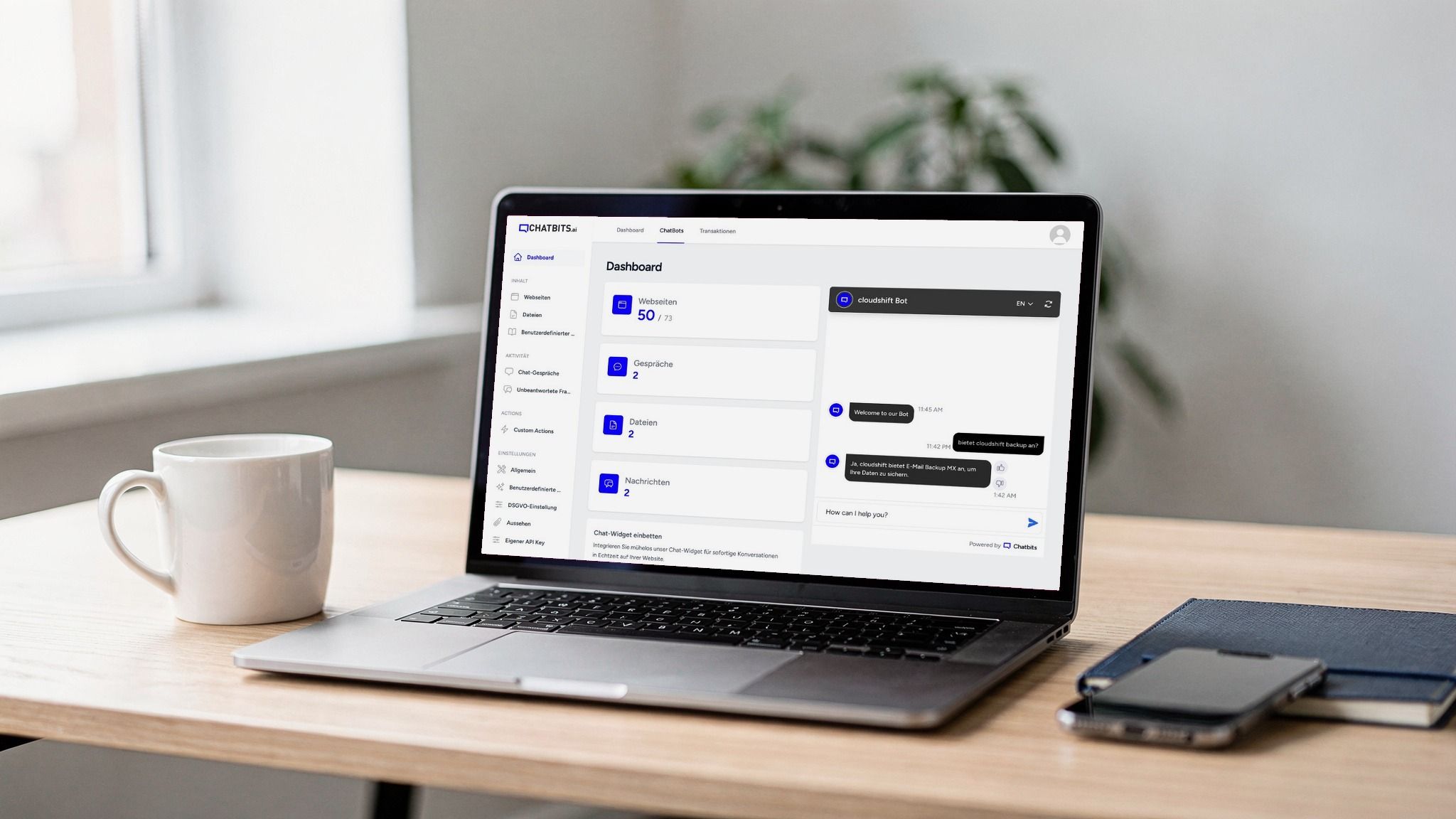 Open laptop on a light wooden desk, its screen showing the dashboard in the Chatbits back end with figures for websites, conversations and files and a chat preview