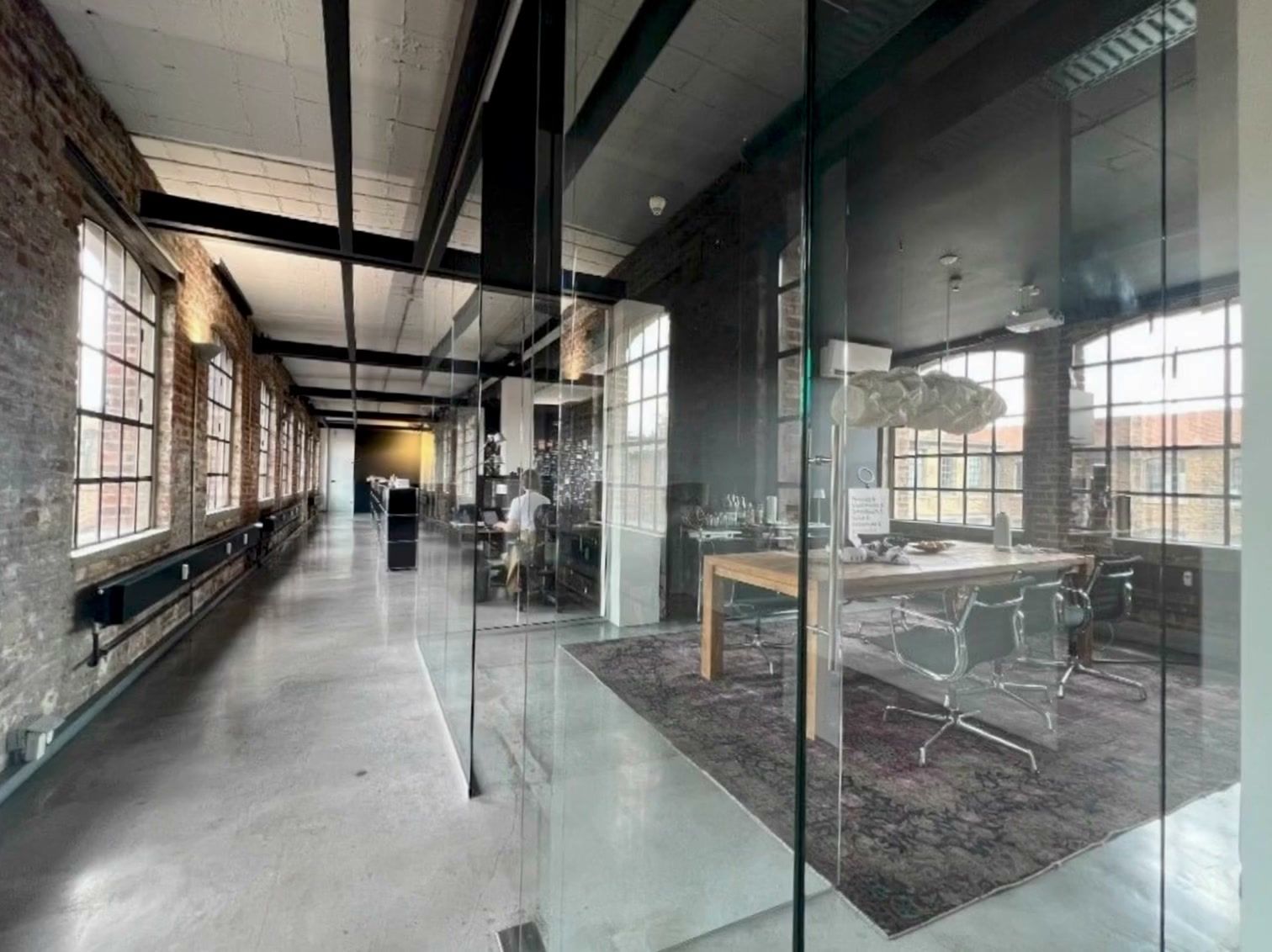 Office with brick walls, a long corridor and a glass meeting room