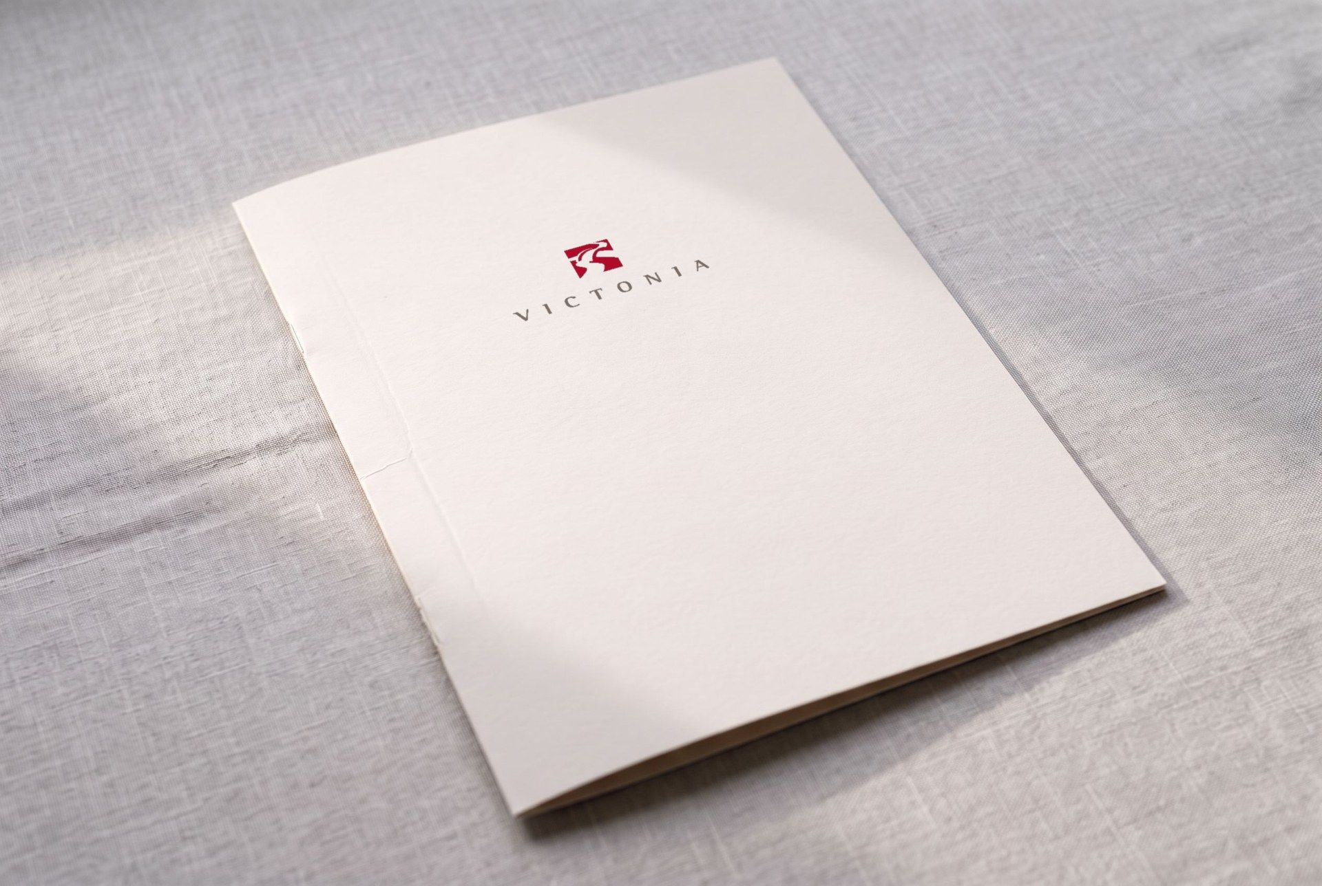 Presentation folder in cream-white card with the Victonia logo