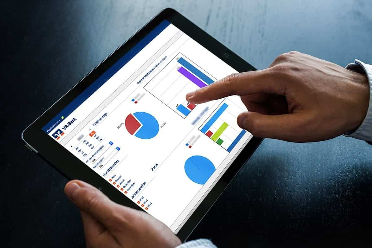 Hand pointing at charts on loan applications and processing times on a tablet